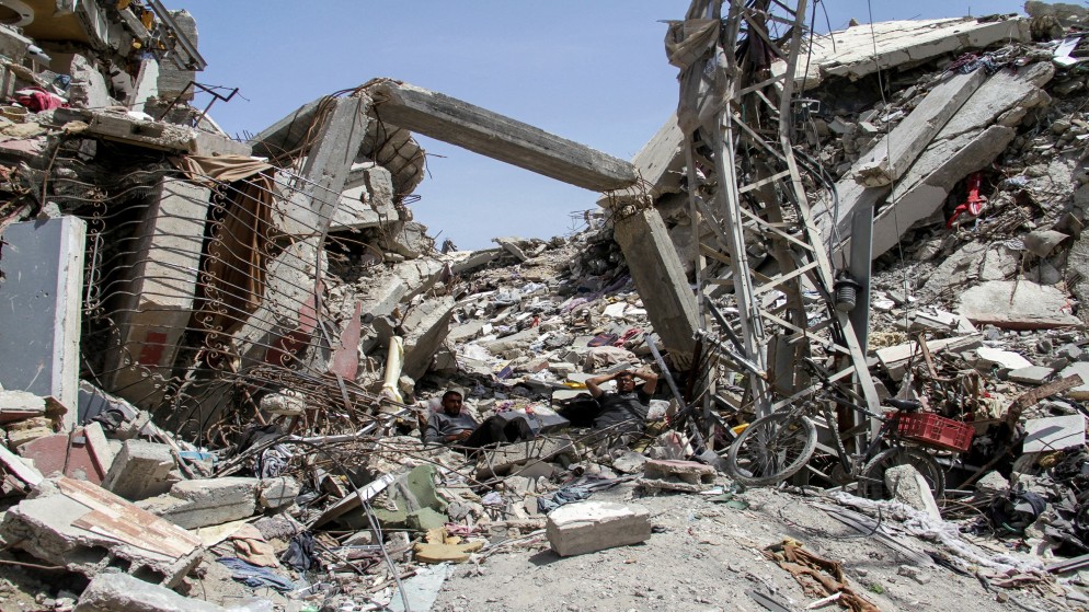 فلسطينيون يستريحون على أنقاض مبنى سكني دمرته الضربات الإسرائيلية في شمال قطاع غزة، 22 نيسان/ أبريل، 2024. (رويترز)