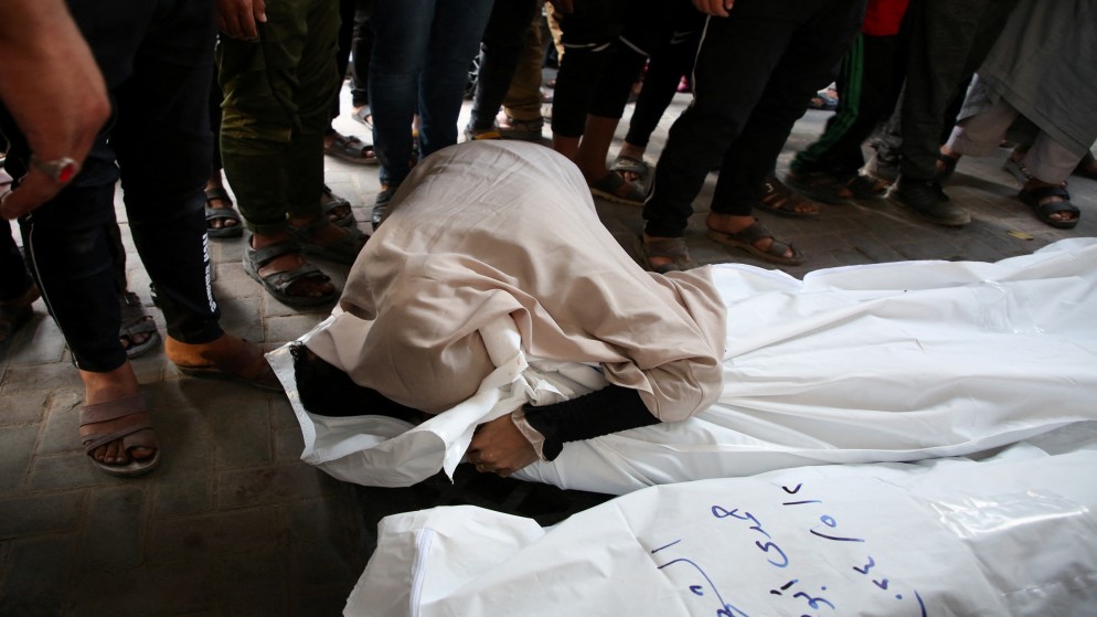 فلسطينية تعانق شهيدا قتلته غارة إسرائيلية في جنوب قطاع غزة. 2 مايو، 2024. (رويترز)