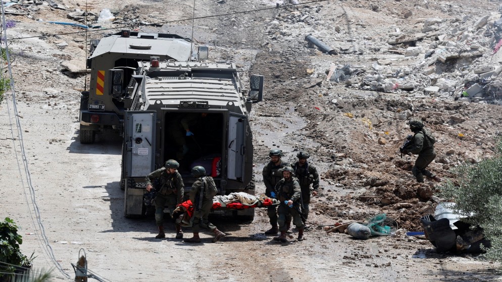 جنود إسرائيليون يحملون نقالة بالقرب من مركبة عسكرية خلال عملية إسرائيلية في دير الغصون قرب طولكرم في الضفة الغربية المحتلة، 4 أيار/مايو 2024. (رويترز)