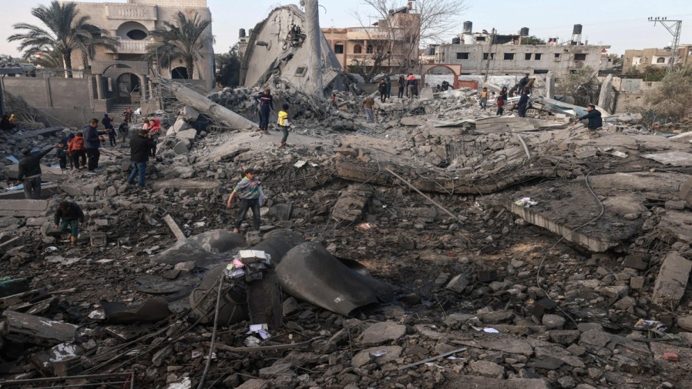 فلسطينيون يبحثون عن أشياء يمكن إنقاذها وسط أنقاض المباني المدمرة في القصف الإسرائيلي. 25 يناير 2024. (أ ف ب)