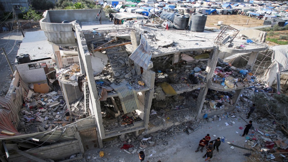 أشخاص يقفون بجوار منزل تضرر في غارة للاحتلال الإسرائيلي على مبنى سكني في رفح جنوبي قطاع غزة. 03/05/2024. (رويترز)