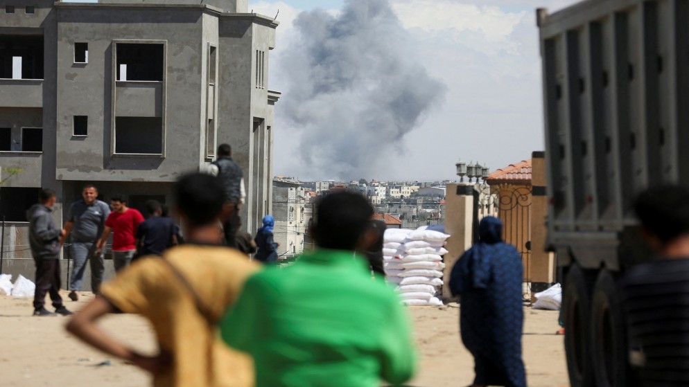 أشخاص ينظرون إلى دخان يتصاعد عقب غارة من الاحتلال الإسرائيلي على رفح جنوبي قطاع غزة، 6 أيار 2024. (رويترز)