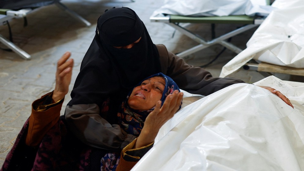نساء يبكين بجانب جثث شهداء فلسطينيين من جراء الغارات الإسرائيلية في رفح جنوبي قطاع غزة، 8 أيار/ مايو، 2024. (رويترز)