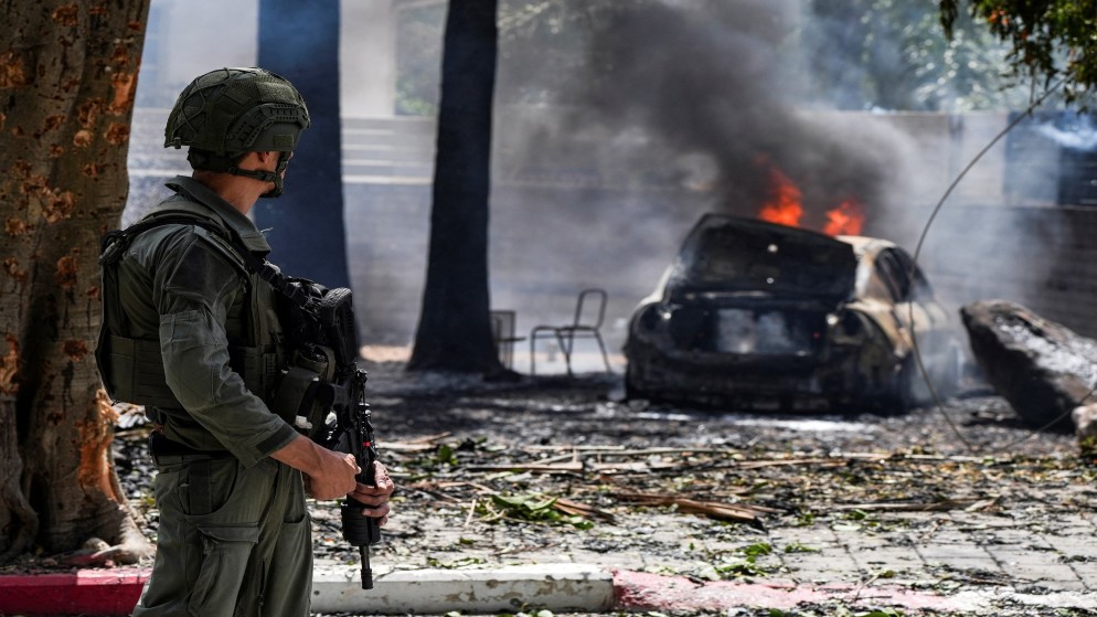 جندي إسرائيلي ينظر إلى سيارة محترقة في موقع سقوط صاروخ أطلق باتجاه إسرائيل من لبنان.5 مايو، 2024. (رويترز)