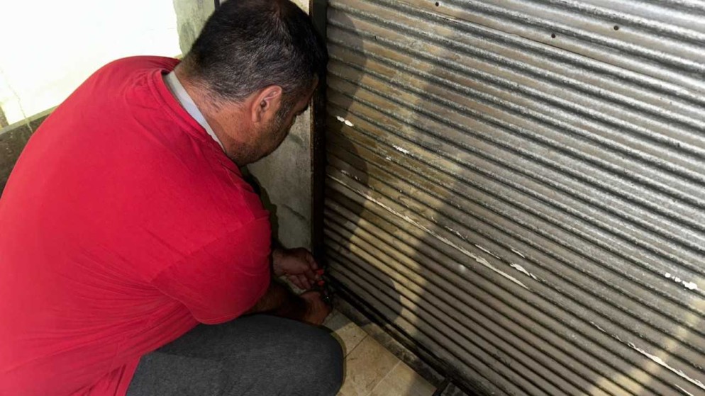 شخص يغلق محلا تجاريا. (بترا)