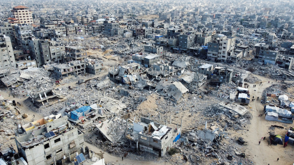 فلسطينيون يسيرون بين أنقاض المنازل والمباني المدمرة في الغارات الإسرائيلية خلال الحرب، في خان يونس في جنوب قطاع غزة، 20 يناير 2025. رويترز