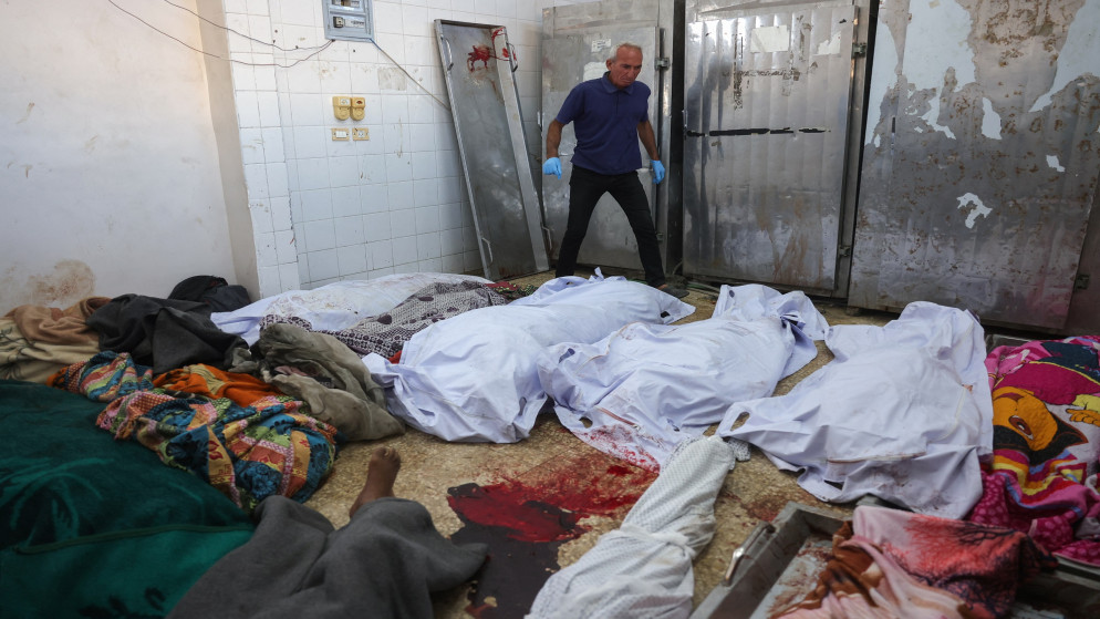 رجل فلسطيني يمشي بين جثث شهداء الغارات الإسرائيلية في دير البلح، في مشرحة مستشفى شهداء الأقصى وسط قطاع غزة، 2 تشرين الأول 2025. (أ ف ب)