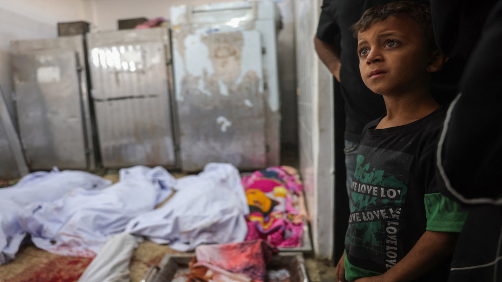 طفل فلسطيني يقف مشدوها ومن خلفه صف من الشهداء في غزة. (أ ف ب)