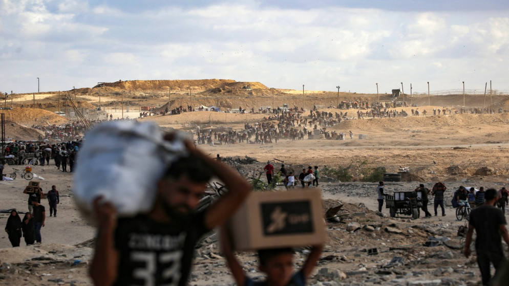 فلسطينيون يحملون حقائبهم عائدين من نقطة توزيع طعام تديرها مؤسسة غزة الإنسانية (GHF)، المدعومة من الولايات المتحدة وإسرائيل، بالقرب من معبر نتساريم وسط قطاع غزة، 5 أكتوبر 2025.(أ ف ب)