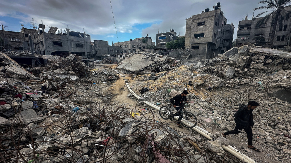 فلسطينيون يسيرون بين الأنقاض يتفقدون منازل دمرتها غارات الاحتلال الإسرائيلية على غزة. (رويترز)
