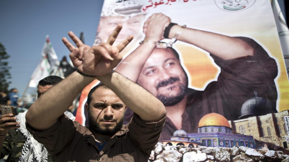 صورة أرشيفية لفلسطيني يقف أمام صورة الأسير مروان البرغوثي. (أ ف ب)