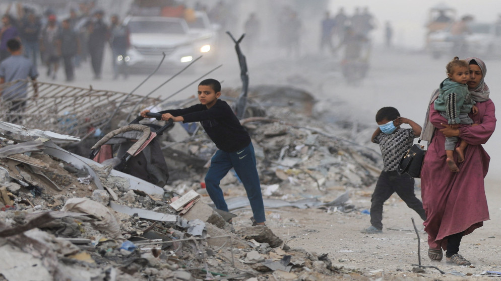 فلسطينيون يسيرون بين الأنقاض بعد انسحاب القوات الإسرائيلية، 12 تشرين الأول 2025. (رويترز)
