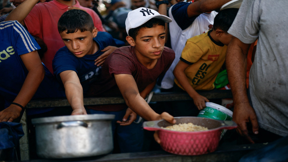 فلسطينيون يتجمعون لتلقي الطعام من مطبخ خيري في مخيم النصيرات وسط قطاع غزة. 07/10/2025. (رويترز)