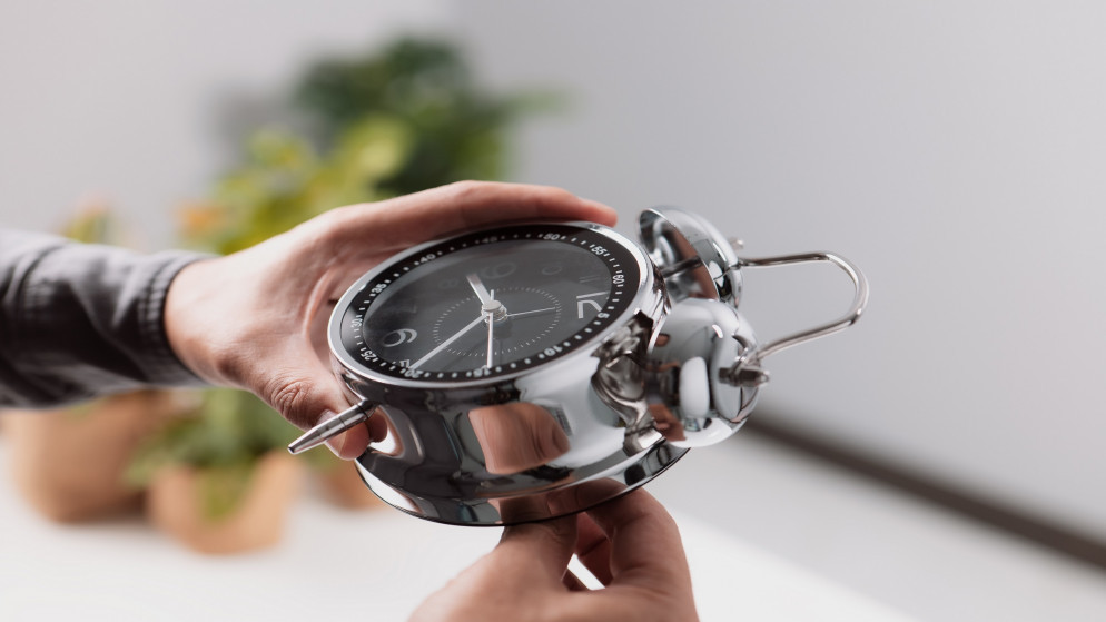 صورة توضيحية لشخص يعدّل الوقت على الساعة. (shutterstock)