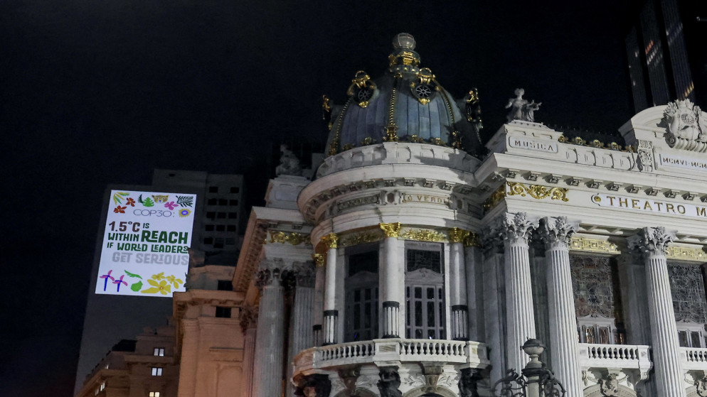 ناشطون بيئيون يعرضون صورا في مبنى قرب المسرح البلدي في البرازيل، مطالبين باتخاذ إجراءات ضد تغير المناخ. 05/11/2025. (أ ف ب)