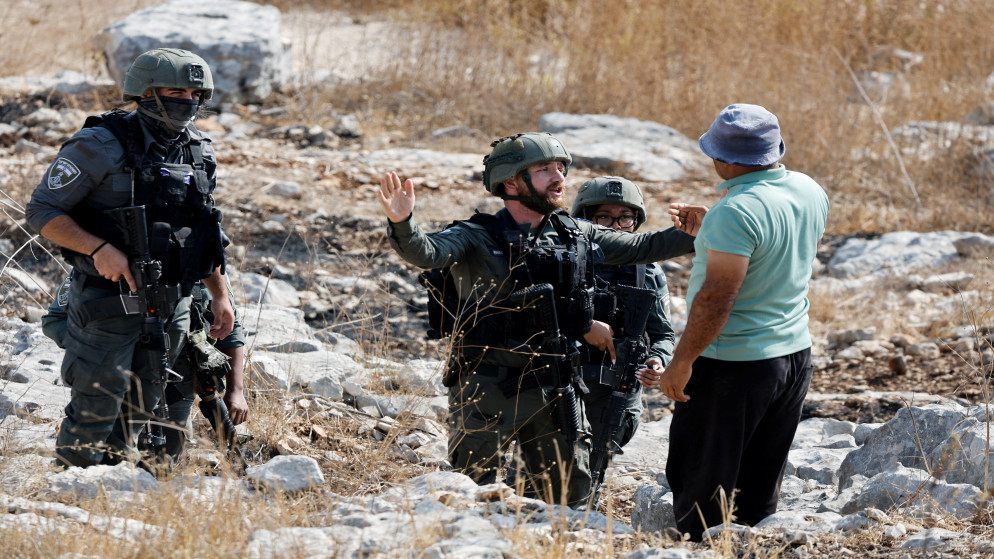 جندي إسرائيلي ورجل فلسطيني يتحدثان خلال تظاهرة منددة بالتوسع الاستيطاني الإسرائيلي في طولكرم، في الضفة الغربية المحتلة، 7 تشرين الثاني 2025. (رويترز)