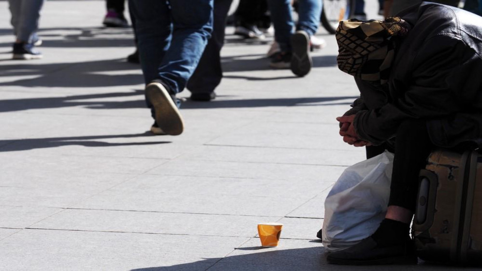 صورة توضيحية لشخص يمارس التسول في شارع رئيسي. (Shutterstock)