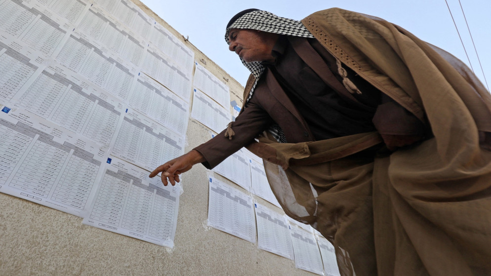 ناخب عراقي يطالع جداول الناخبين. (أ ف ب)