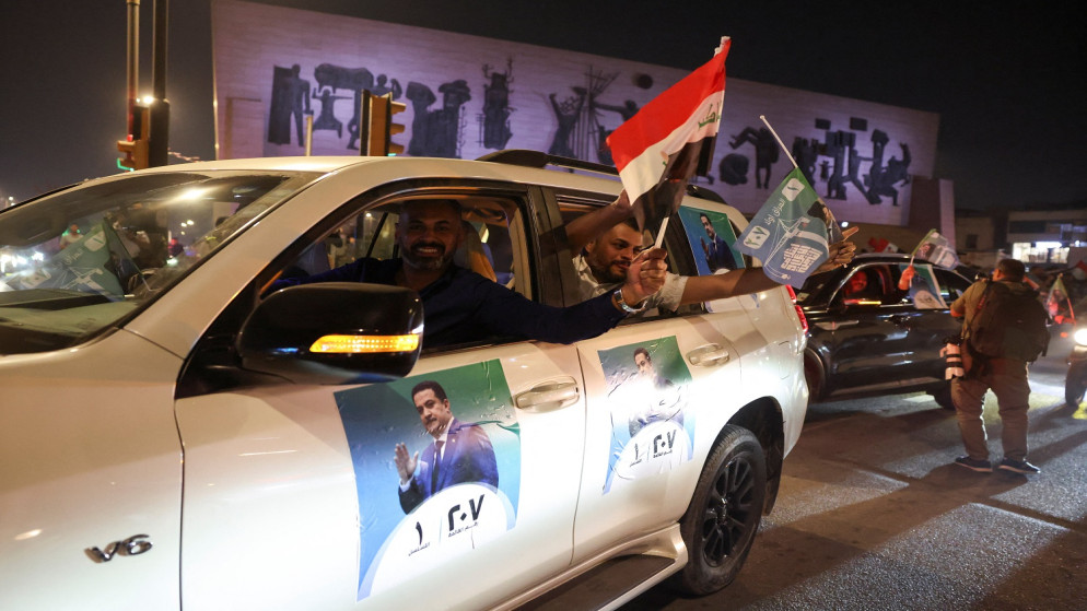 سيارة تحمل ملصقات انتخابية تظهر رئيس الوزراء العراقي الحالي محمد شياع السوداني، بينما يحتفل أنصار ائتلاف إعادة الإعمار والتنمية بعد الإعلان عن النتائج الأولية للانتخابات في بغداد، العراق، 12 تشرين الثاني 2025. (رويترز)