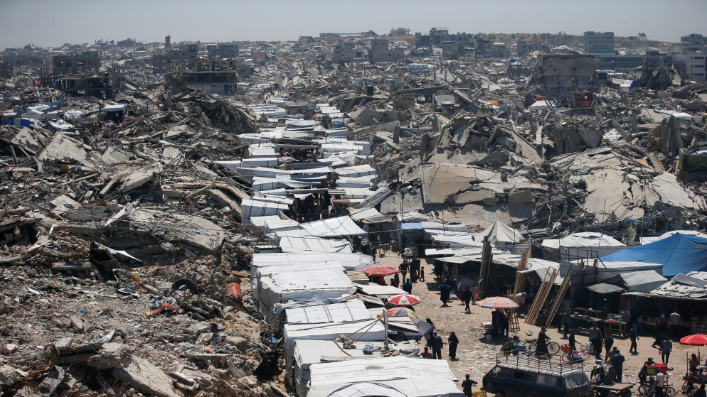 فلسطينيون يتسوقون في سوق بالقرب من أنقاض المنازل في مخيم جباليا للاجئين، شمال قطاع غزة، 8 أيار 2025. (رويترز)