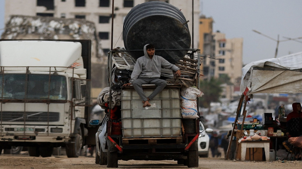 شاب فلسطيني يجلس على خزان مياه بجوار خيام في يوم ممطر، خلال وقف إطلاق النار بين إسرائيل وحماس، في مدينة غزة، 14 تشرين الثاني 2025. (رويترز)