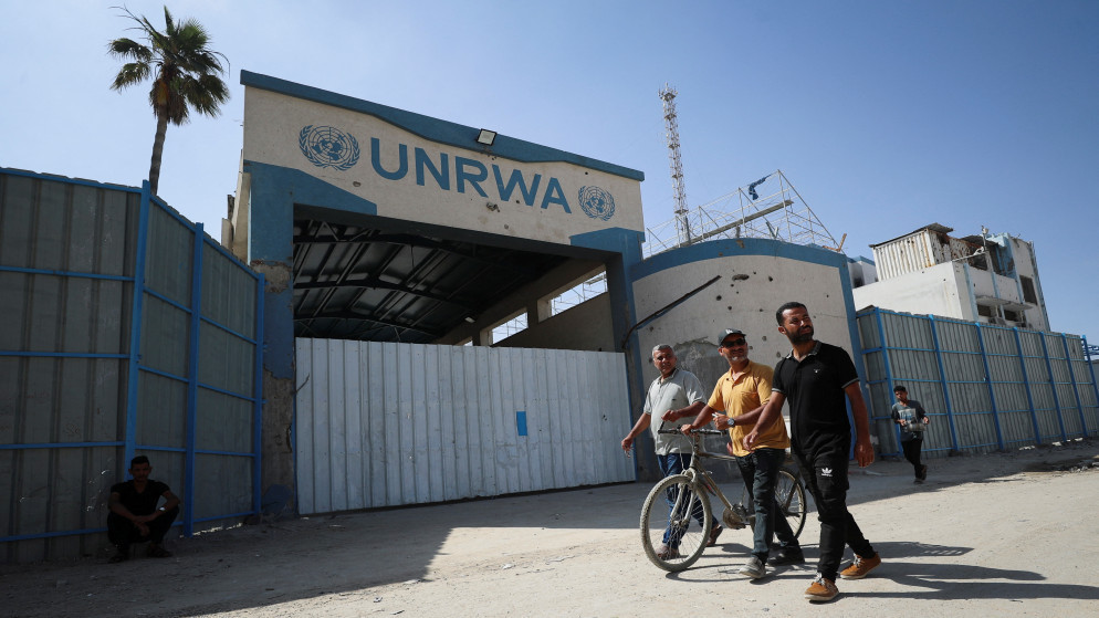 فلسطينيون يسيرون أمام مركز تابع لوكالة غوث وتشغيل اللاجئين الفلسطينيين (الأونروا)  في مدينة غزة. 20 أيار 2025. (رويترز)