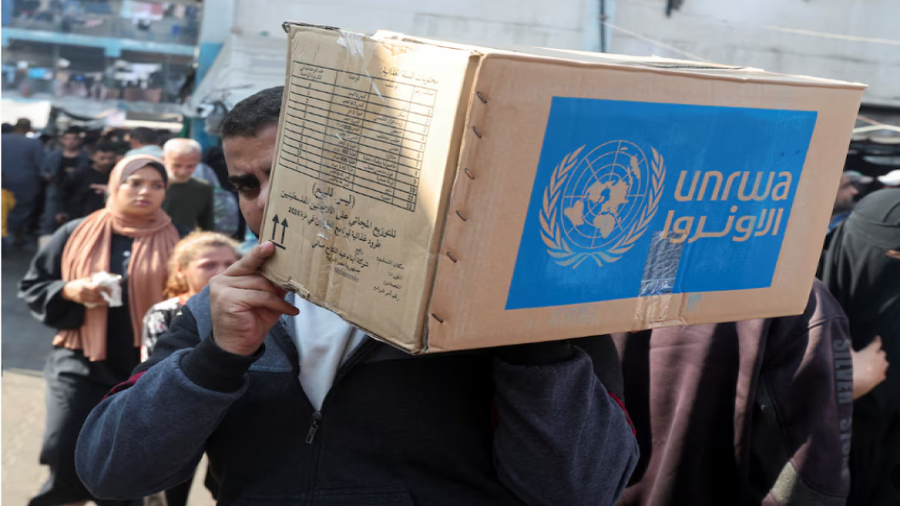 فلسطيني يحمل صندوق مساعدات من وكالة الأونروا. (رويترز)