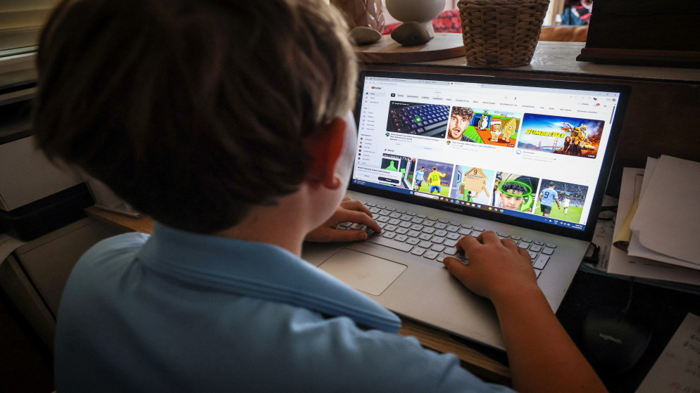 فتى في الرابعة عشرة من عمره يقف في منزله وهو يتصفح مواقع التواصل الاجتماعي على حاسوبه. (أ ف ب)