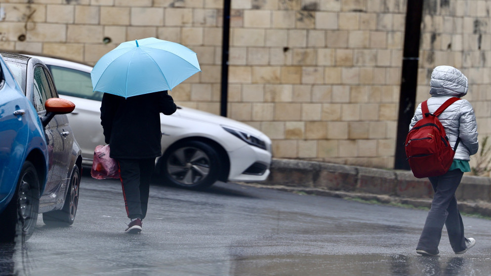 طالبة تسير باتجاه المدرسة في جو ماطر. (المملكة)
