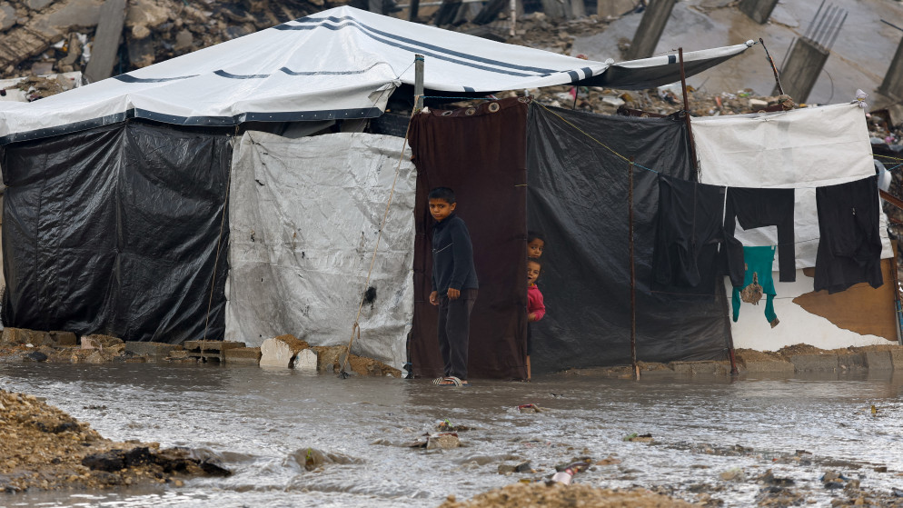 أطفال فلسطينيون نازحون يحتمون في مخيم مغمور بالمياه، خلال يوم ممطر في مدينة غزة، 25 تشرين الثاني 2025. (رويترز)