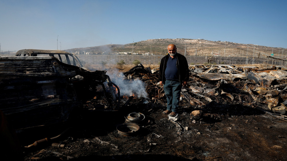 يقف الفلسطيني محمد دلال (57 عاما) بين السيارات التي أحرقت في هجوم شنّه مستوطنون إسرائيليون في حوارة بالضفة الغربية المحتلة، 21 تشرين الثاني 2025. (رويترز/ عمار عواد)