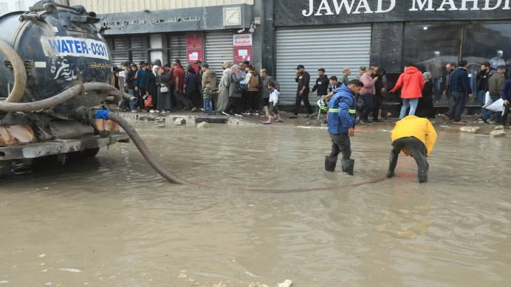 أحد كوادر بلدية غزة وهو يحاول تصريف مياه أمطار الشتاء في المدينة.