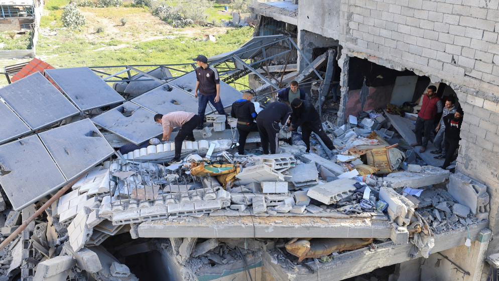 فلسطينيون يتفقدون موقع غارة إسرائيلية على مبنى سكني في مدينة غزة، 19 آذار 2025. (رويترز)