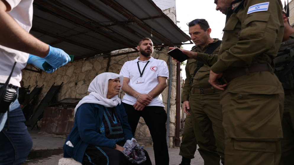امرأة فلسطينية مسنة على كرسي متحرك عند نقطة تفتيش عسكرية في بيت لحم، بالضفة الغربية المحتلة، في 28 مارس/آذار 2025.(أ ف ب)
