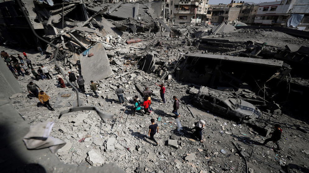 فلسطينيون يتفقدون موقع غارة إسرائيلية على قطاع غزة. 18 آذار 2025. (رويترز)