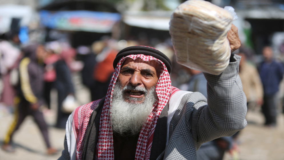 رجل فلسطيني يتسلم الخبز من أحد المخابز في خان يونس، جنوب قطاع غزة، 9 آذار 2025. (رويترز)