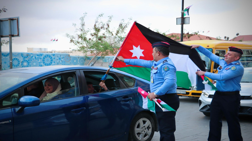 رجال الأمن العام يوزّعون الأعلام احتفاء بيوم العلم الأردني.