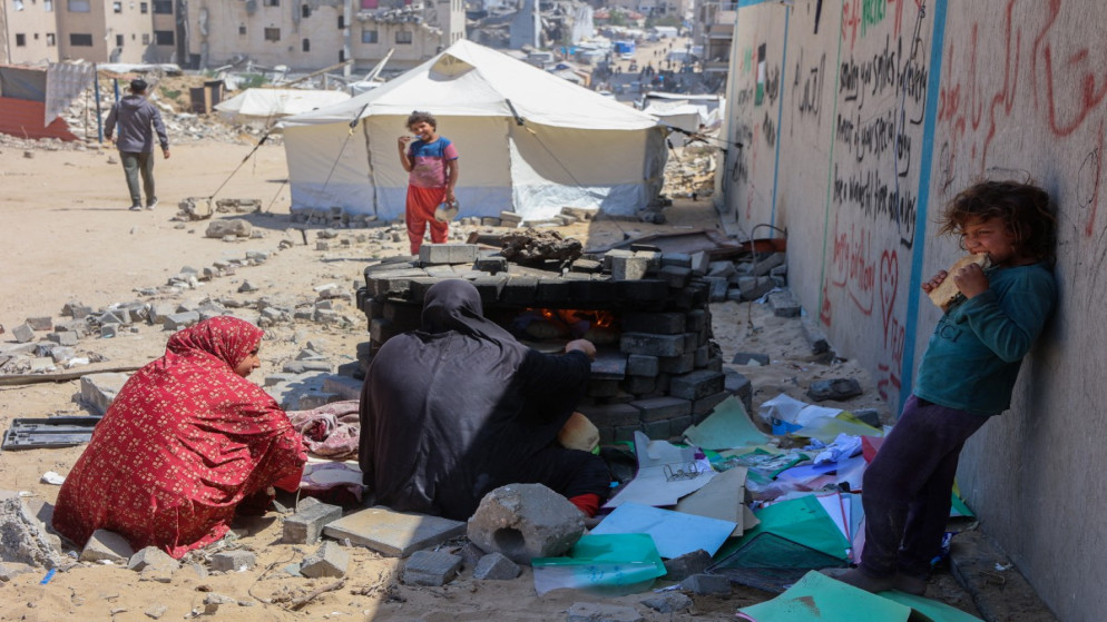 فلسطينيات يخبزن في فرن خارجي مؤقت قرب خيام النازحين في مدينة غزة. 1 مايو/أيار 2025. (أ ف ب)
