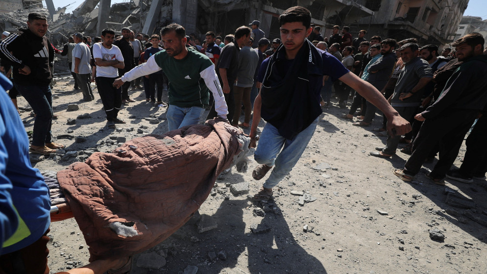 فلسطينيون يحملون جثمان شهيد أثناء بحثهم عن ضحايا في موقع غارة إسرائيلية على منزل في جباليا شمالي قطاع غزة. 2 أيار 2025. (رويترز)