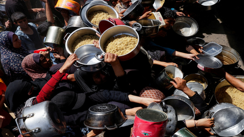 فلسطينيون يتجمعون لتلقي الطعام الذي أعدته جمعية خيرية في خان يونس، جنوبي قطاع غزة، 29 نيسان 2025. (رويترز)