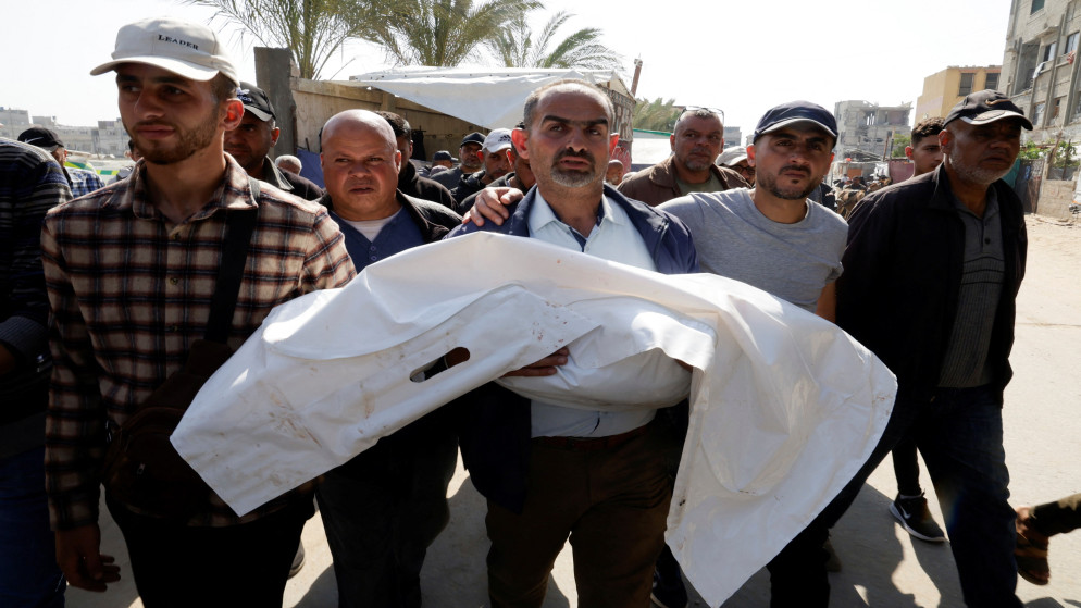 فلسطيني يحمل جثمان طفل في مستشفى ناصر في خان يونس استشهد في غارة للاحتلال الإسرائيلي. قطاع غزة. 19 أبريل 2025. (رويترز)
