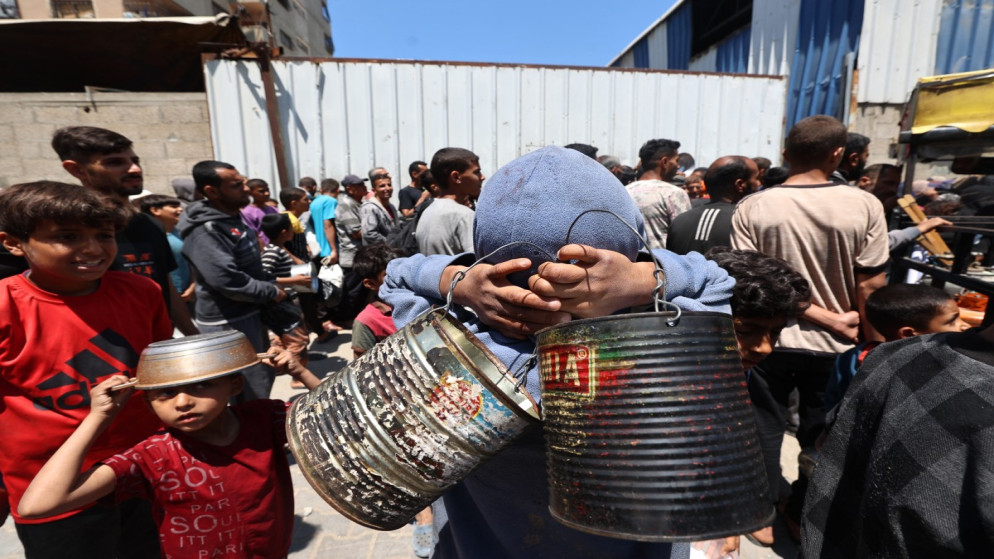 فلسطينيون يصطفون للحصول على طعام في مطبخ خيري بمخيم النصيرات وسط قطاع غزة، 4 مايو/أيار 2025. (أ ف ب)