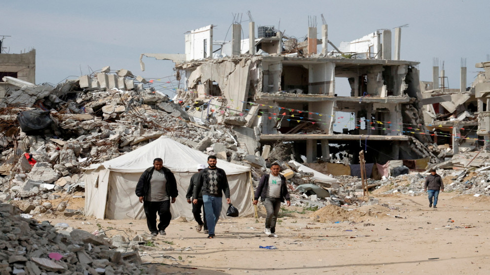 فلسطينيون يسيرون بالقرب من أنقاض المنازل التي دمرت خلال العدوان الإسرائيلي على مدينة رفح جنوب قطاع غزة. 13 مارس 2025. (رويترز)