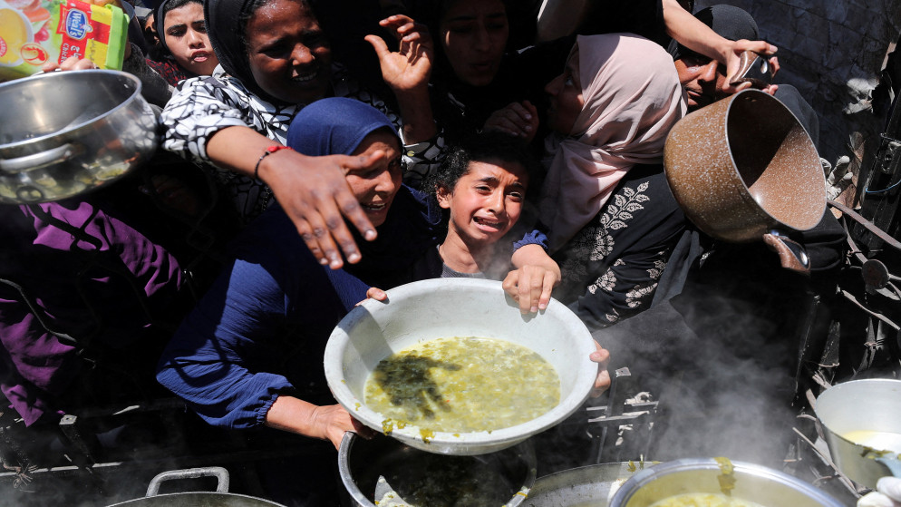 فلسطيني يتلقى طعاما مطهو في مطبخ في بيت لاهيا شمال قطاع غزة. 8 مايو/أيار 2025. (رويترز)