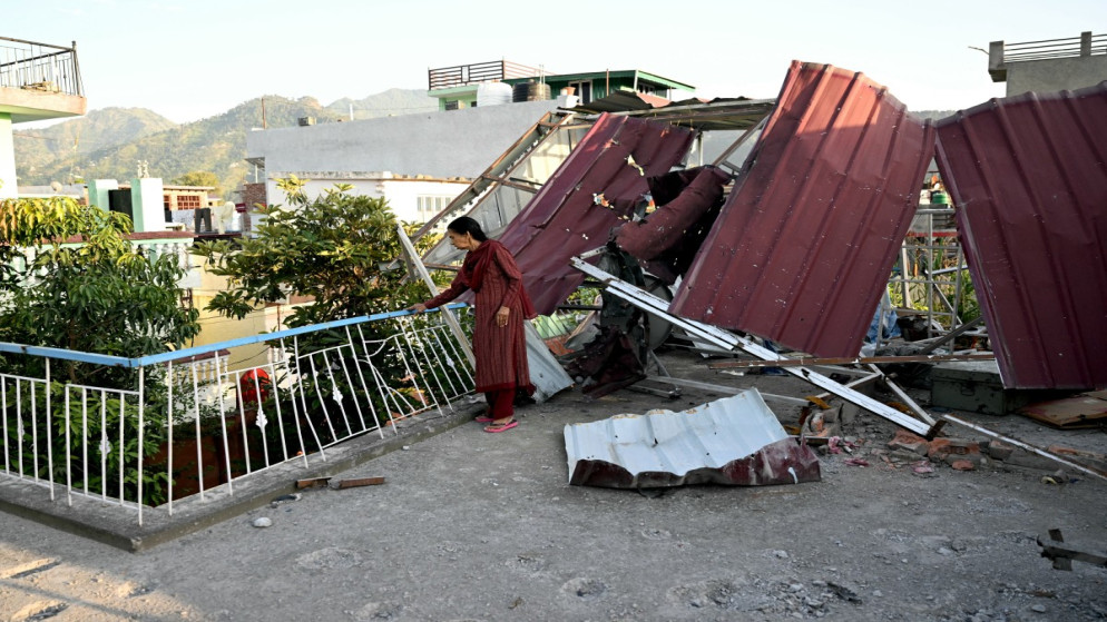 سيدة هندية تقف أمام منزلها المتضرر بعد أن أطلقت باكستان صواريخ في بونش بكشمير. 14 مايو/أيار 2025. (أ ف ب)