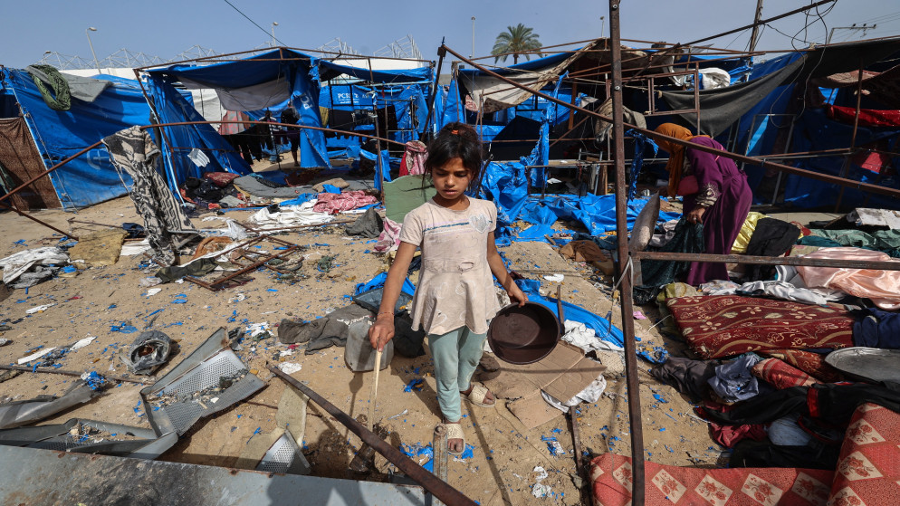 فلسطينيون يبحثون عن أغراض قابلة للإنقاذ في ملاجئ مُدمّرة إثر غارات جوية إسرائيلية ليلية، وسط قطاع غزة، في 17 أيار 2025. (أ ف ب)