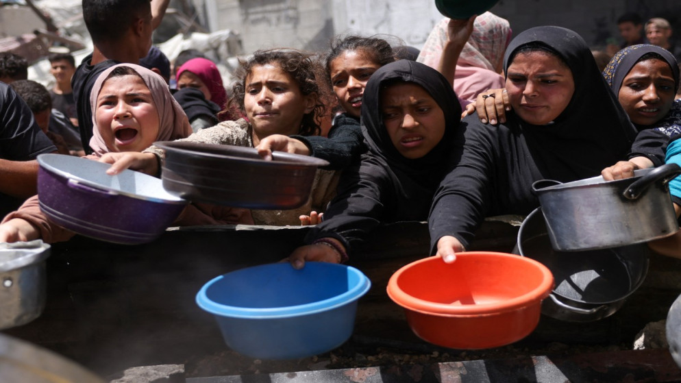 نازحون فلسطينيون يتجمعون لاستلام حصص من الطعام المطبوخ في مخيم خيري بجباليا شمالي قطاع غزة، 19 أيار 2025. (أ ف ب)
