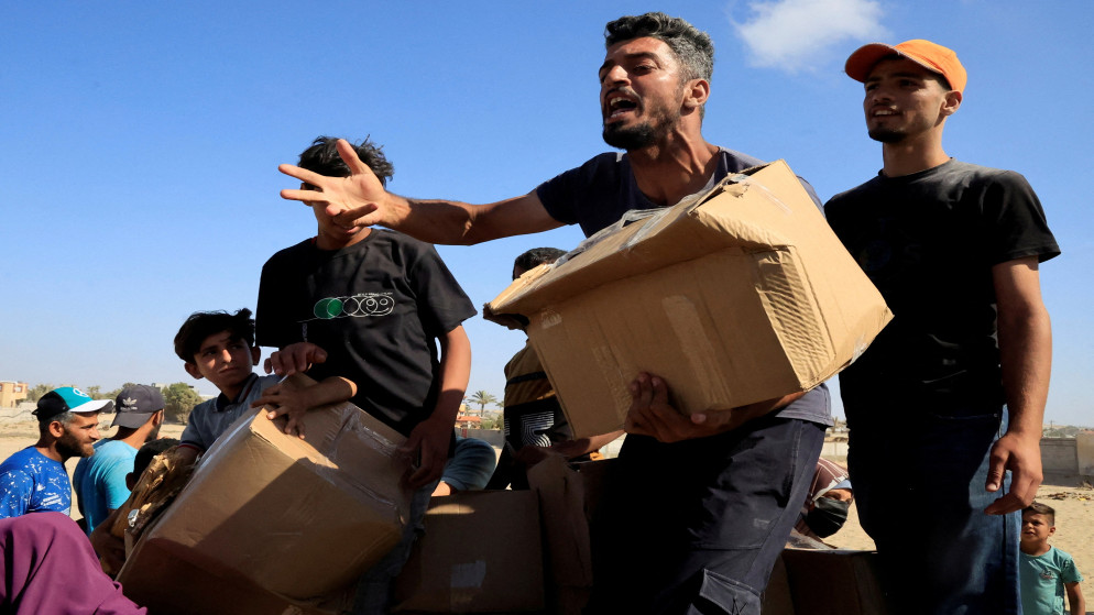 نازحون فلسطينيون يحملون طردا غذائيا بالقرب من موقع توزيع مساعدات تديره مؤسسة غزة الإنسانية في رفح جنوب قطاع غزة. 27 مايو 2025. (رويترز)