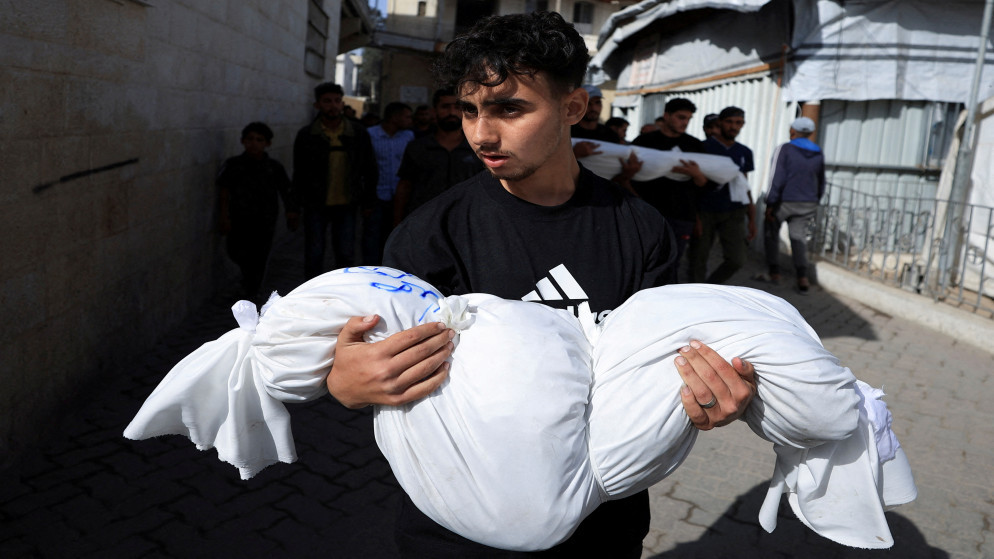 فلسطيني يحمل جثمان شهيد في مستشفى المعمداني الأهلي العربي في مدينة غزة، 26 أيار 2025. (أيار)