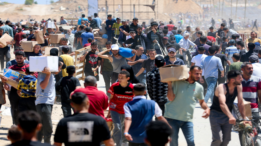 فلسطينيون يحملون مساعدات تلقوها من مؤسسة غزة الإنسانية، 29 أيار 2025. (رويترز)